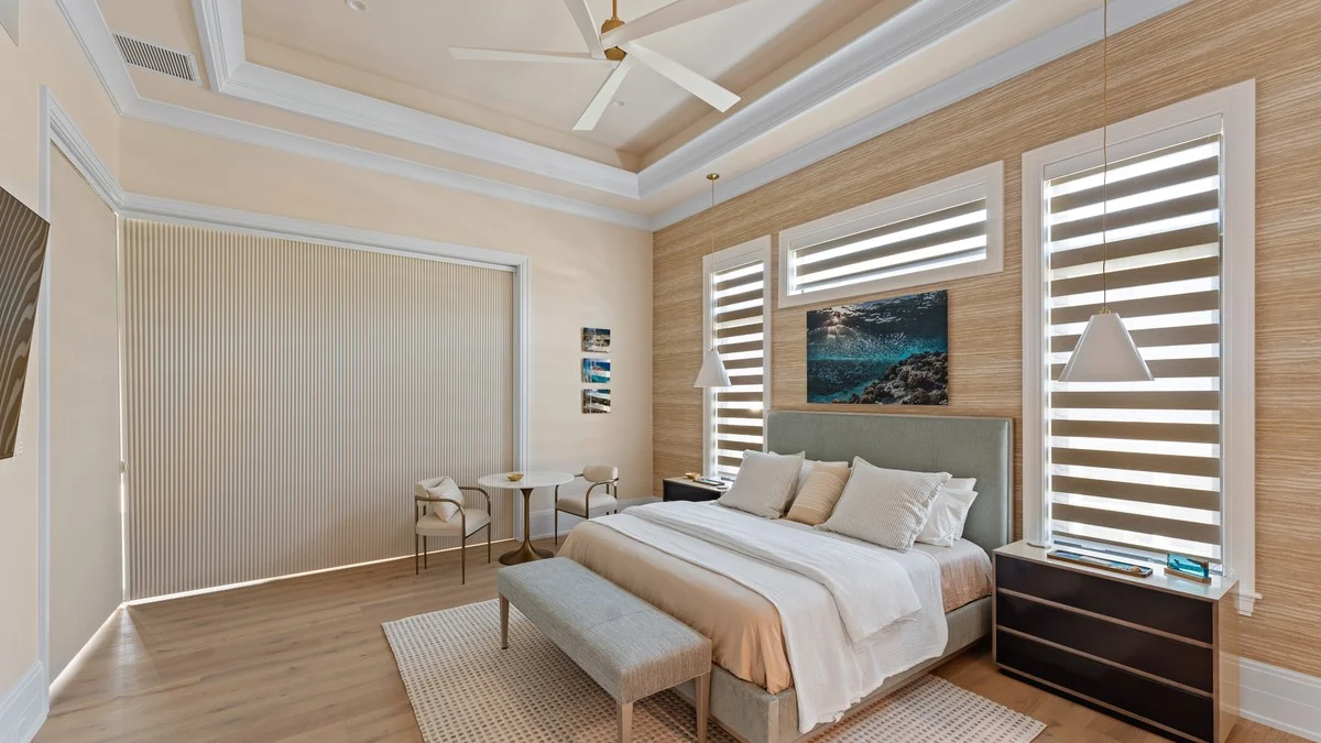 Coordinated roller shade and shutters in a bright coastal bedroom
