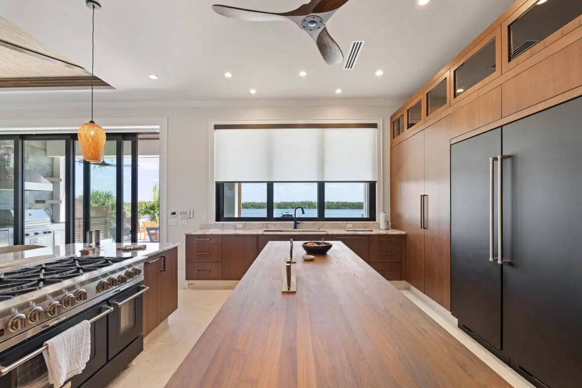 White roller shade partially lowered over a wide kitchen window
