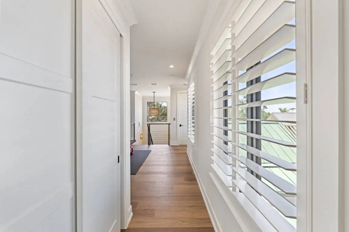 White plantation shutters along a sunlit hallway
