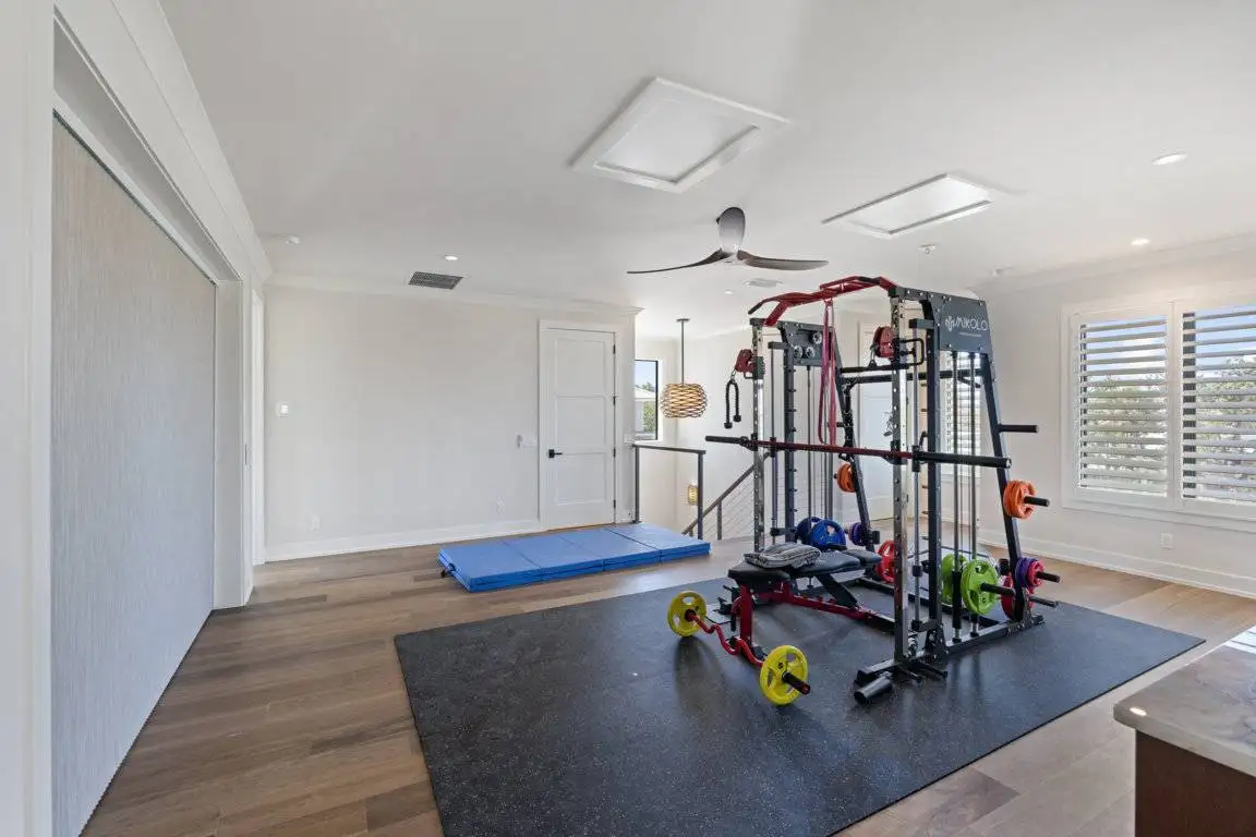 Wide fabric window covering and white plantation shutters in a home gym