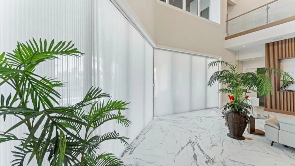Close view of light-filtering honeycomb shade material across a large glass wall