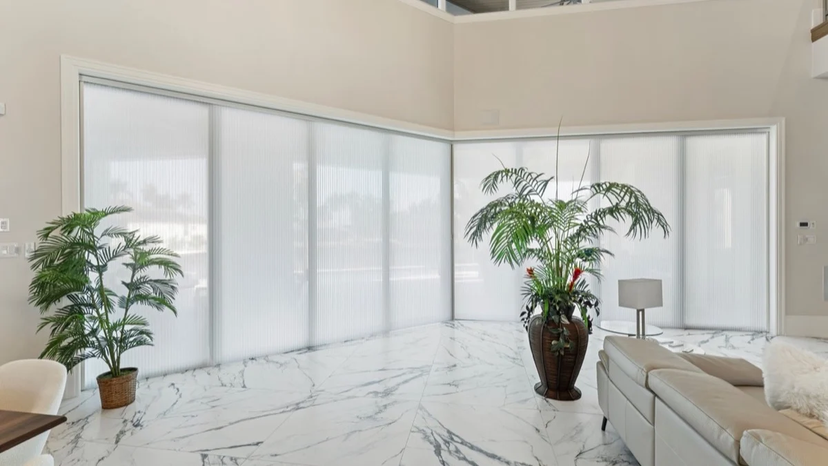 Light-filtering honeycomb shades covering adjoining walls of corner glass