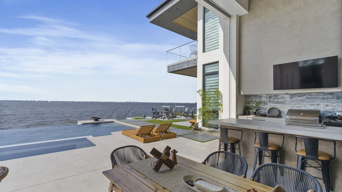Completed covered outdoor kitchen with a television, bar stools and waterfront seating