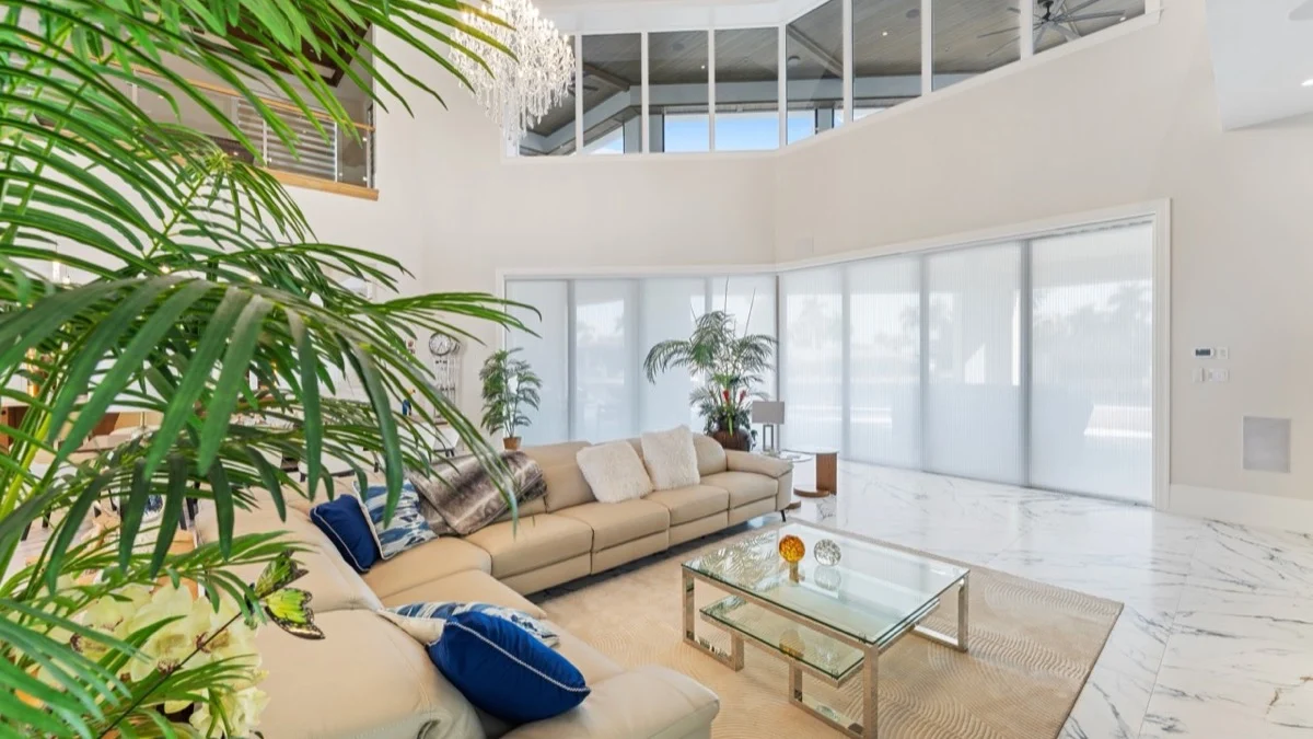 Light-filtering cellular shades across oversized glass in a Southwest Florida waterfront-style living room