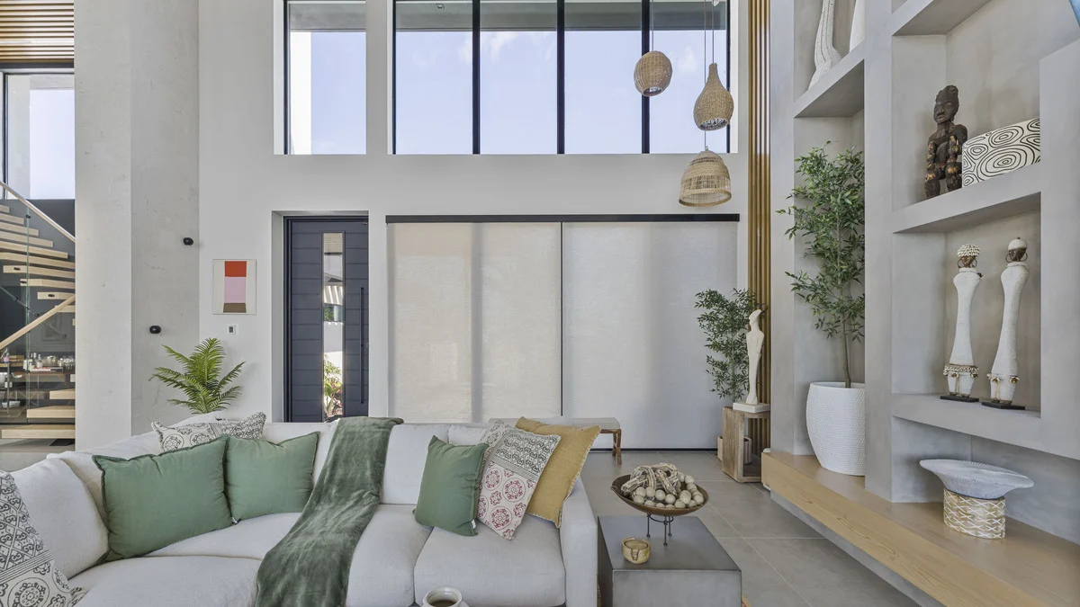 Roller shades lowered across the great-room window wall beside white display shelves