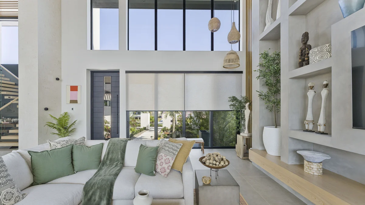 Partially lowered roller shades beside white display shelves in the completed living room