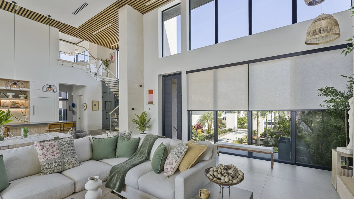 Roller shades covering the lower great-room glazing while the high transom windows remain uncovered
