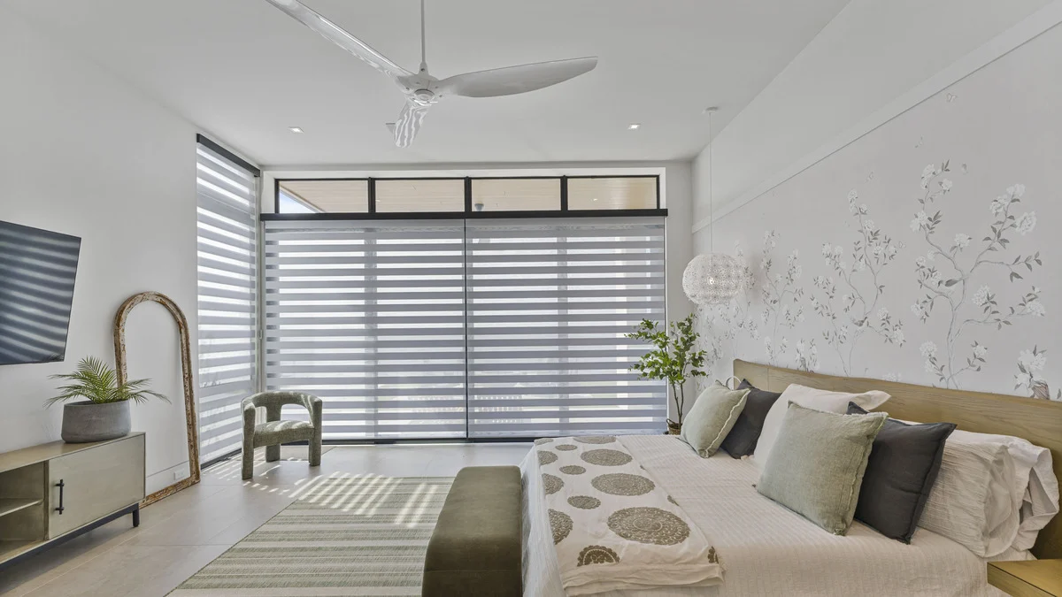 Zebra shades lowered over primary-bedroom sliding doors beneath uncovered transom windows